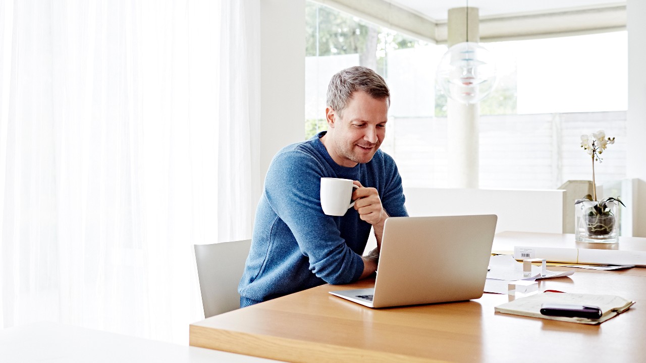 A man using computer with a coffee in his hand; image used for HSBC SecureMail.