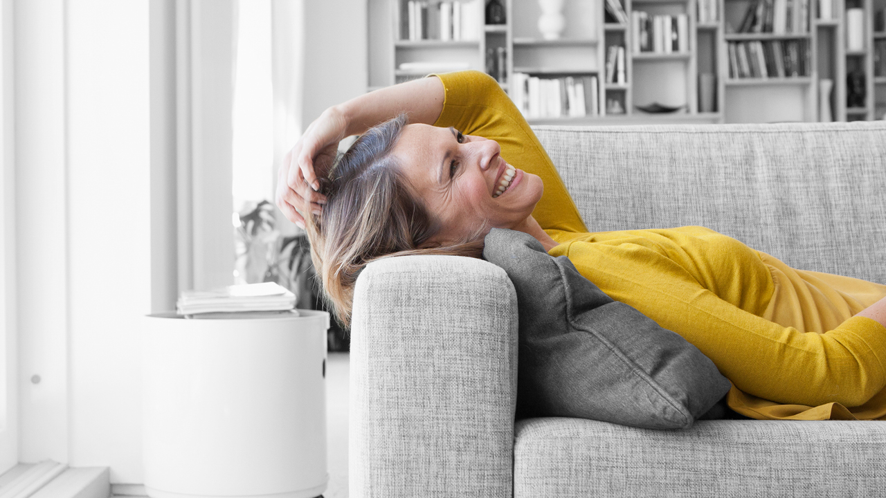 A smiling woman lying down on sofa; image used for HSBC Australia What is Balance transfer.
