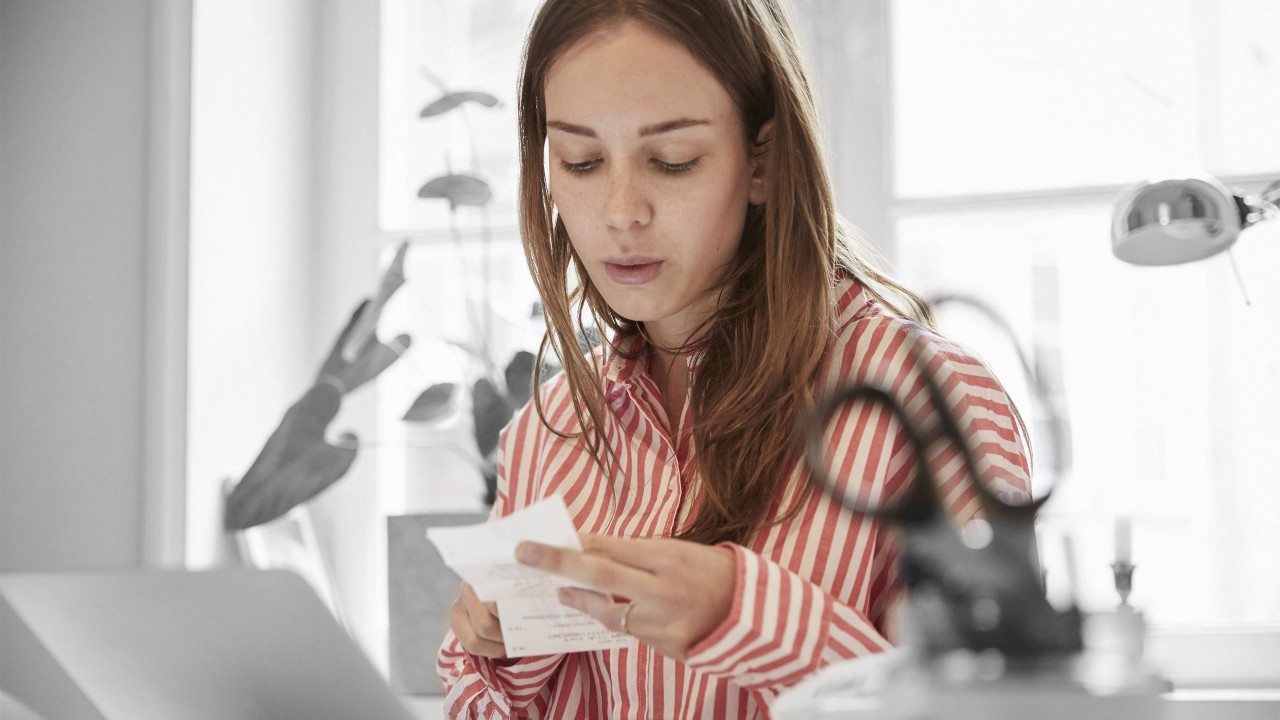 A young woman checking financial bill; image used for HSBC Australia How to make it easier to pay off multiple debts. 