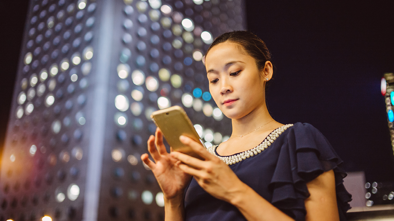 An Asian lady is using mobile phone; image used for HSBC Australia Mobile Banking.