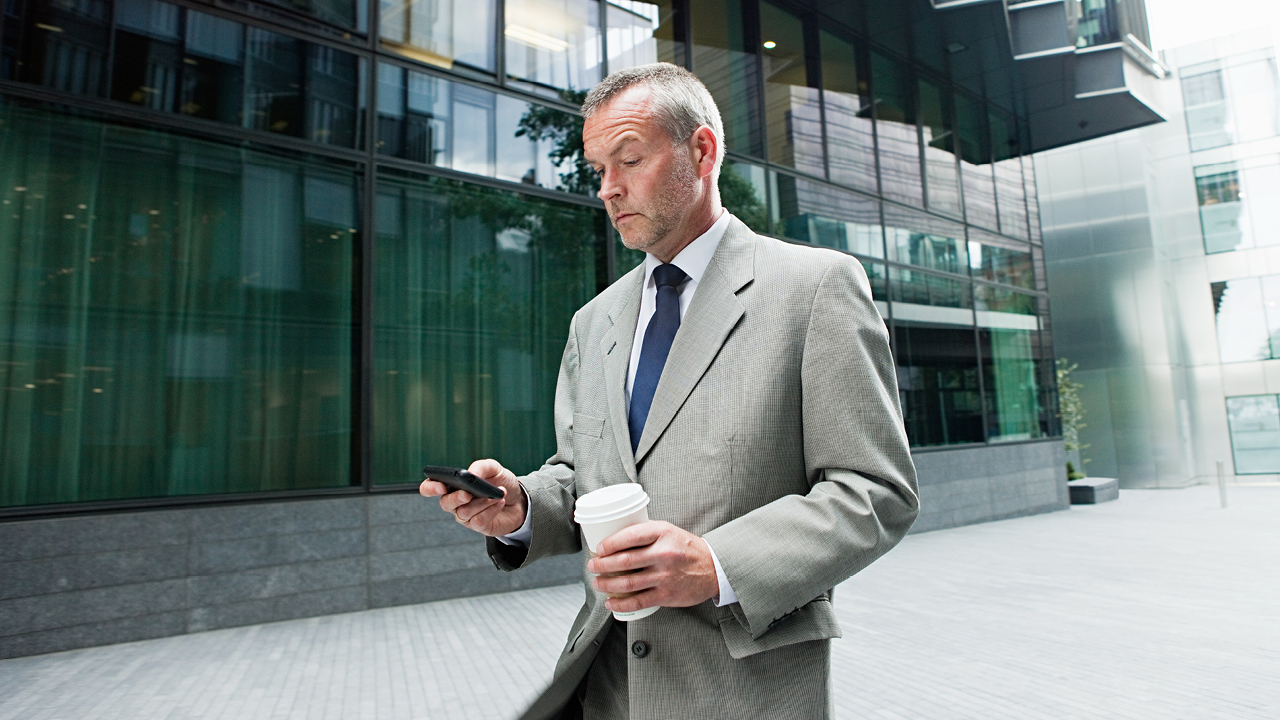Businessman checking phone with a cup of coffee; image used for HSBC Australia trading platform. Platforms
