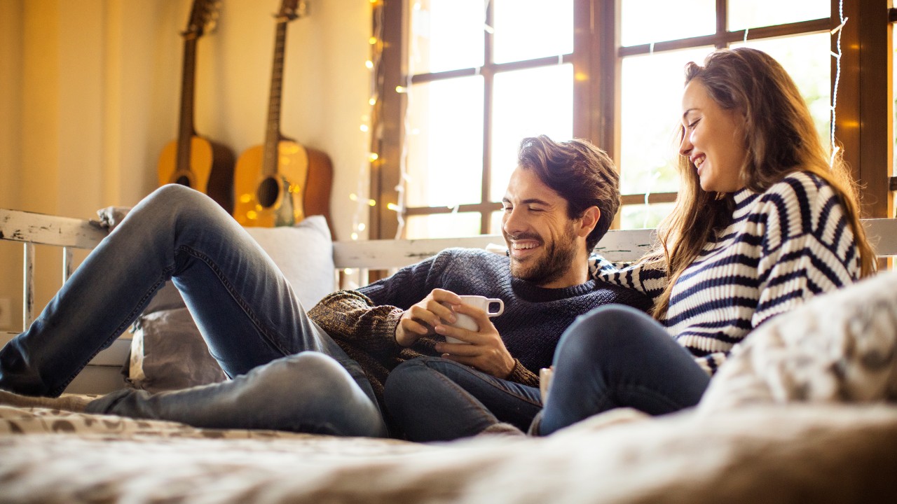 Happy couple having coffee while resting on alcove window seat at homer; image used for HSBC bank account.