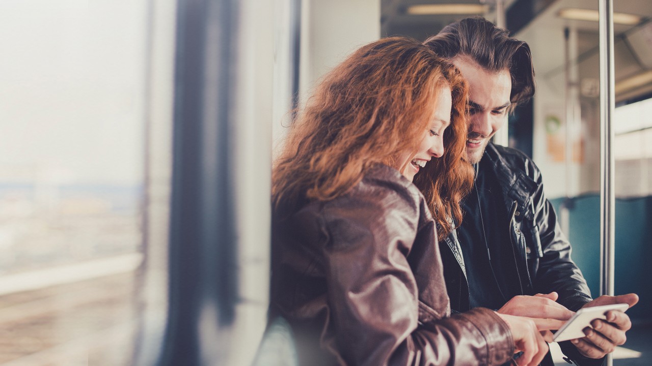 A couple using smartphone together on train; image used for HSBC The easiest way to pay your bills.