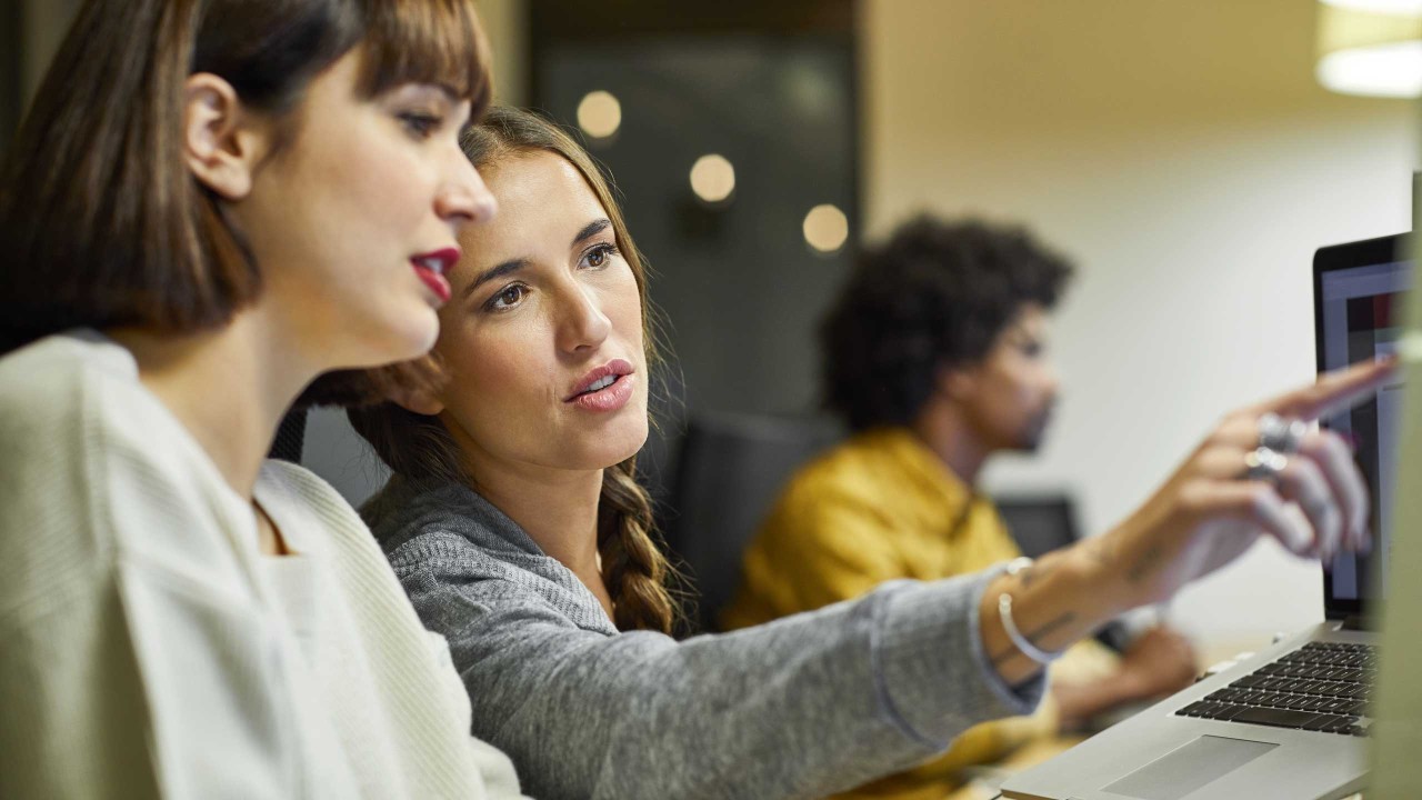 Two female business professionals discussing over computer in office; image used for HSBC Australia Security Centre page.