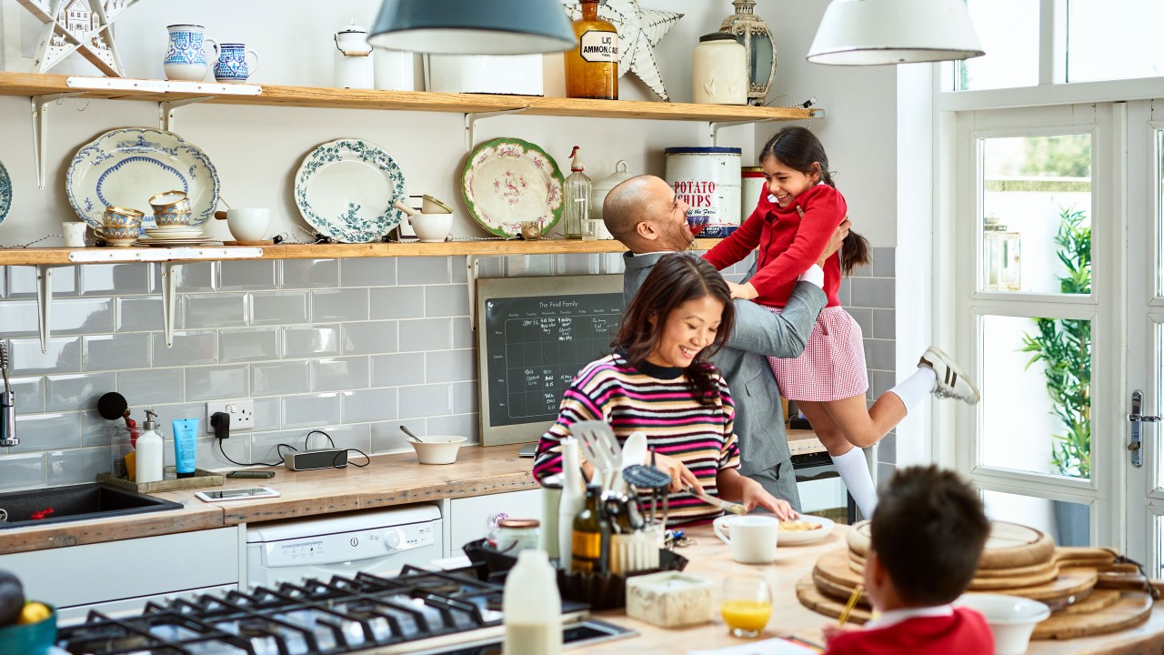 Father lifting daughter and mother making breakfast; image used for HSBC Australia retrieve your Home loans application.