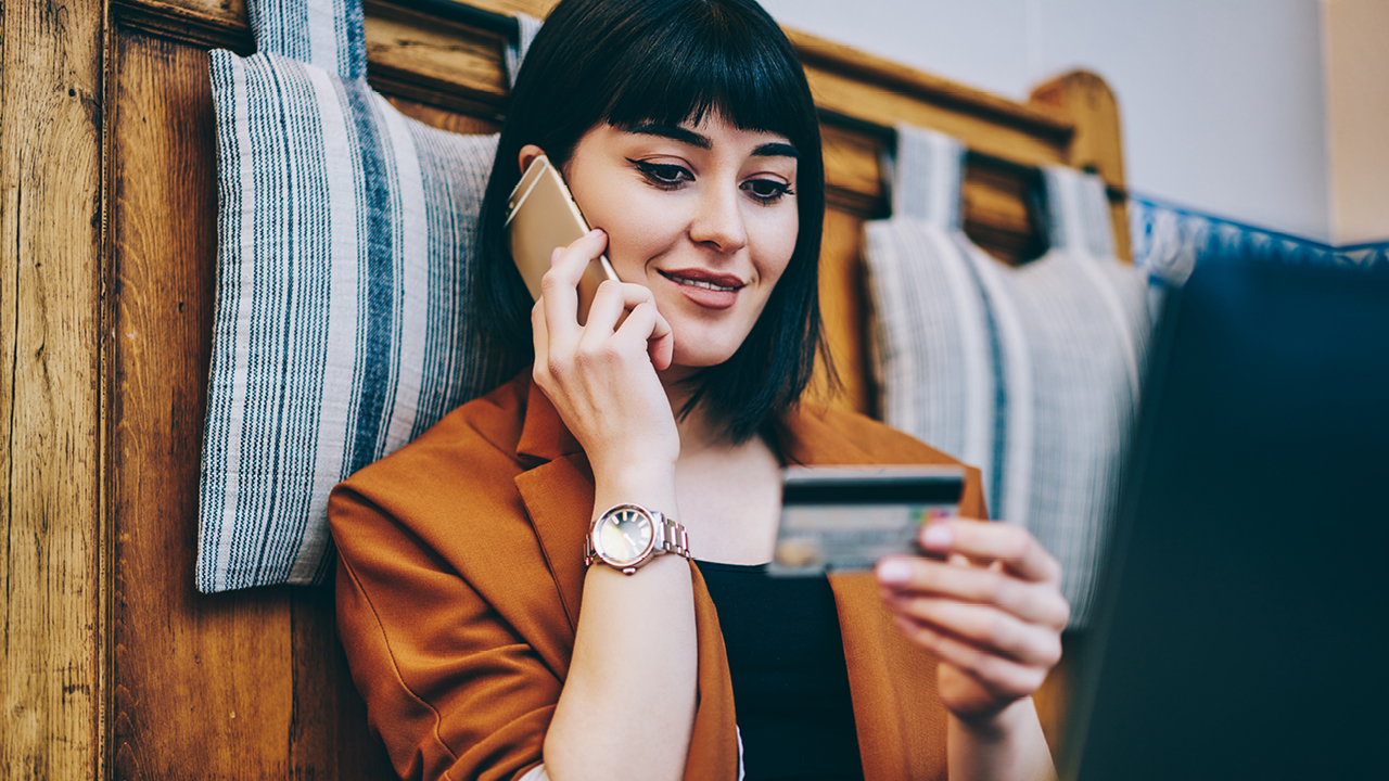 A lady is looking at her credit card while she's on the phone; image used for HSBC Australia activate your credit card