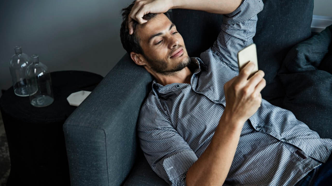 A man using phone on sofa; image used for HSBC Credit Cards Balance Transfers offer page.