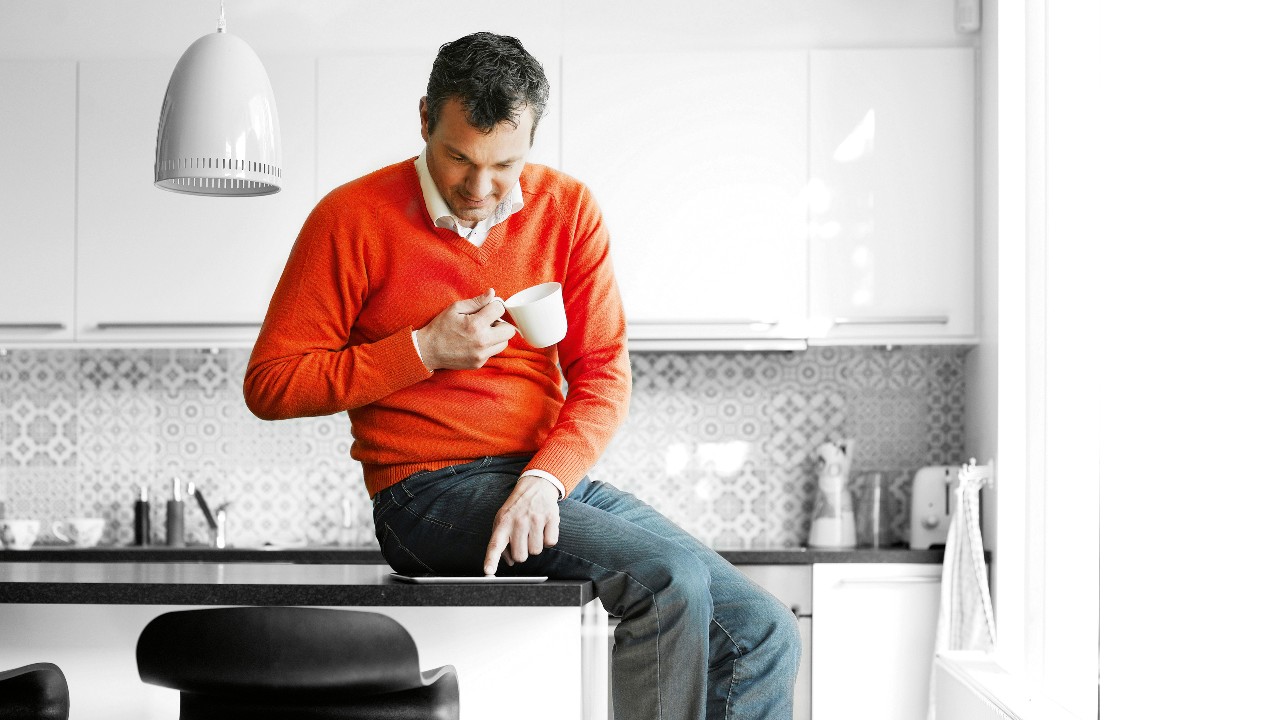 A person using tablet and holding a coffee mug on hand; image used for HSBC Foreign Currency Compare Accounts.