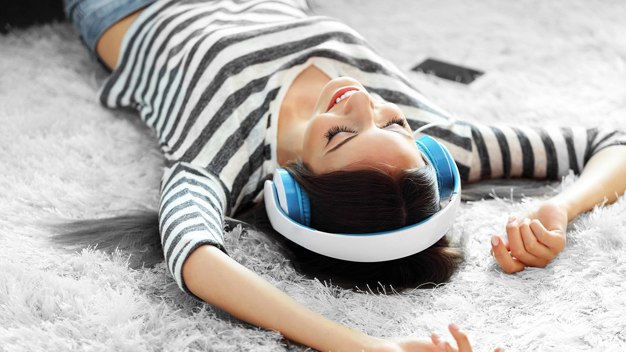 A woman listening music and lying down on a carpet; image used for HSBC Australia Instant savings.