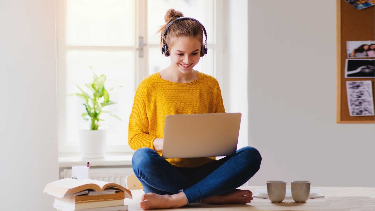 A smiling woman using laptop and sitting on the table; image used for HSBC Australia Your HSBC guide on how to save money. 