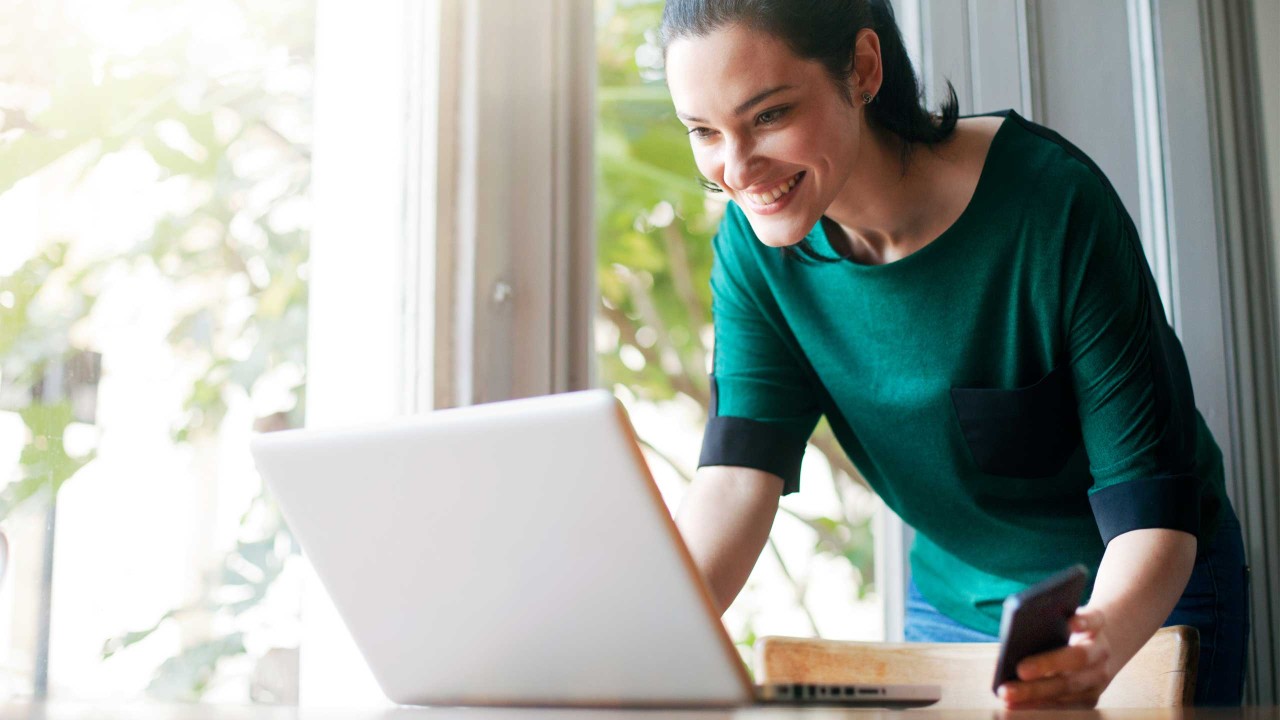 A woman using laptop with smart phone; image used for HSBC Australia Switch to HSBC.