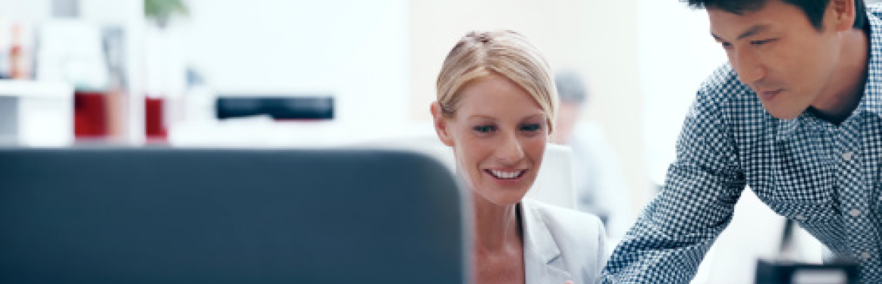 A man showing information to a woman in front of a computer; image used for HSBC Australia banking support.