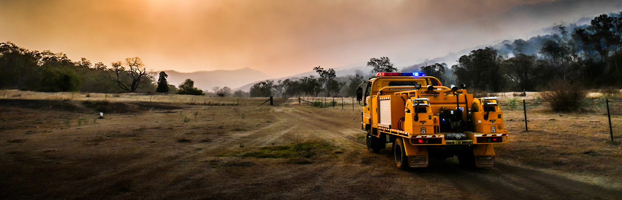 Fire truck approaches distant smoke; image used for Australia bushfire crisis.