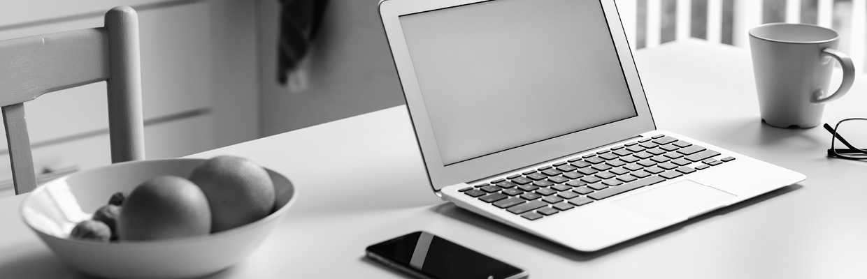 A desk with laptop, mobile, a bowl of fruits and a cup of water; image used for HSBC Australia Ways to bank.