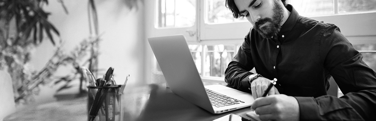 A man writing with laptop; image used for HSBC Australia debt consolidation page.