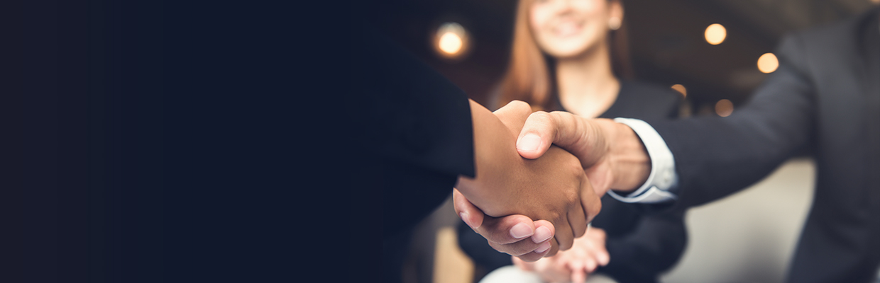 Two people are shaking hands while a girl is sitting in the background; image used for HSBC Markets Desk.