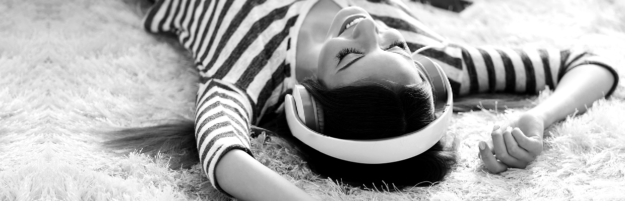 A woman listening music and lying down on a carpet; image used for HSBC Australia Instant savings.