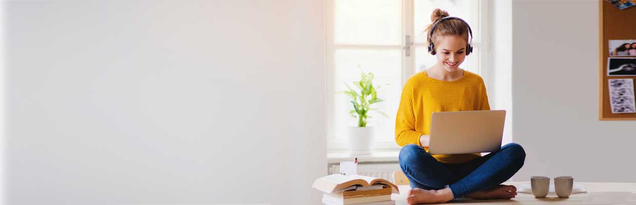 A smiling woman using laptop and sitting on the table; image used for HSBC Australia Your HSBC guide on how to save money. 