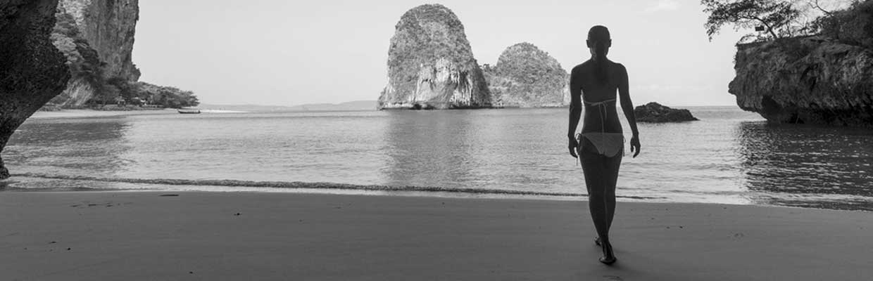 Woman walking on beach with rocks; image used for HSBC Australia credit card cash transfer.