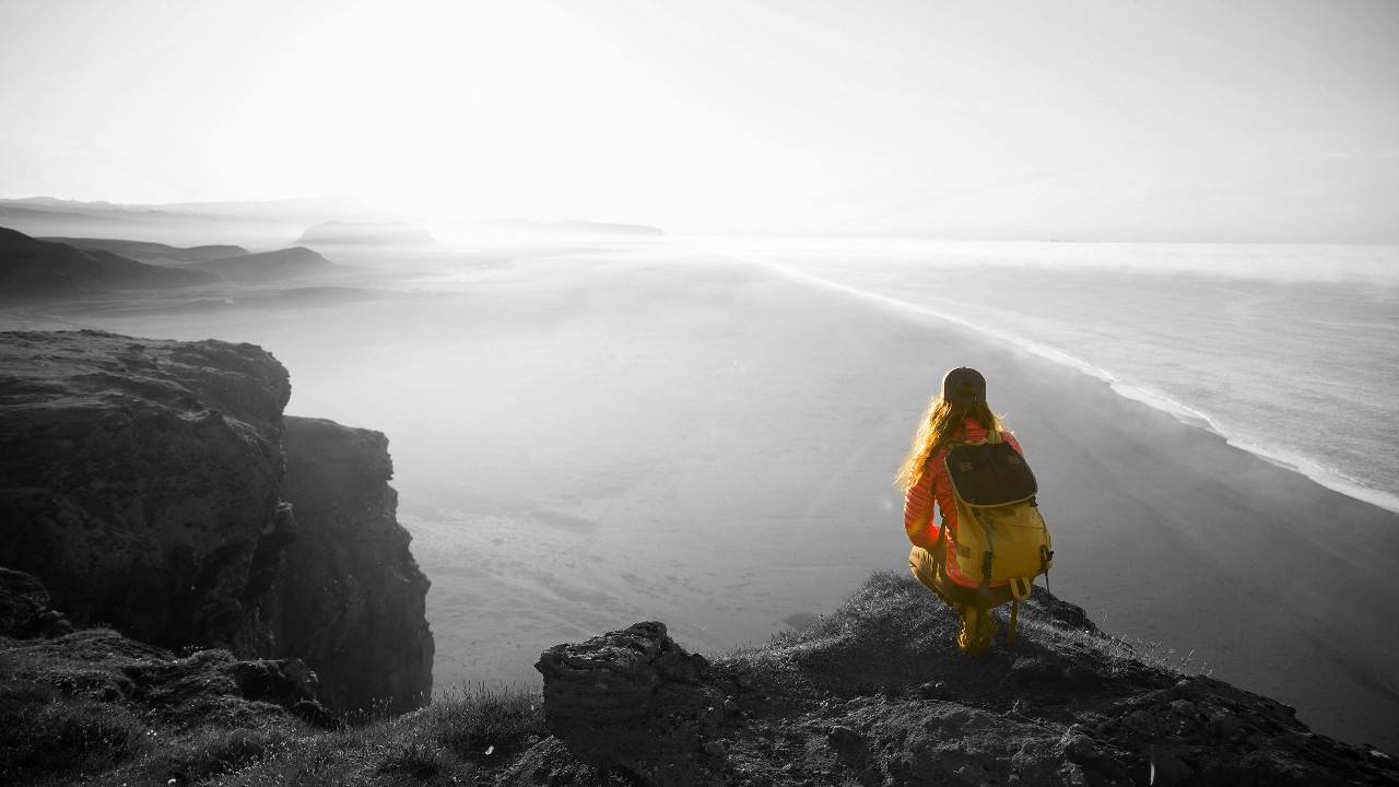 A Hiker with backpack squatting on top of a mountain and enjoying the view; image used for HSBC Australia Everyday Global Account page.