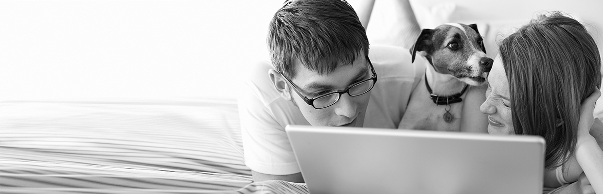 A couple using laptop with their puppy on bed; image used for HSBC Australia finding the right property