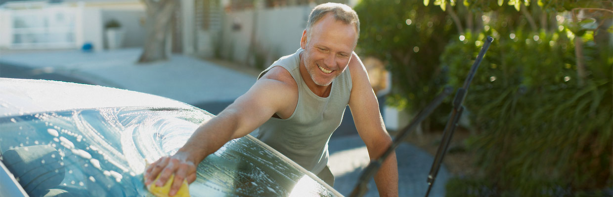 Smiling woman drinking water outside her car; image used for HSBC Car Insurance page.