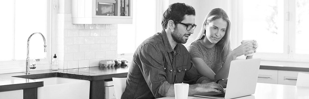 A pair of couple checking with laptop in kitchen; image used for HSBC Austuslia First home buyer hub.
