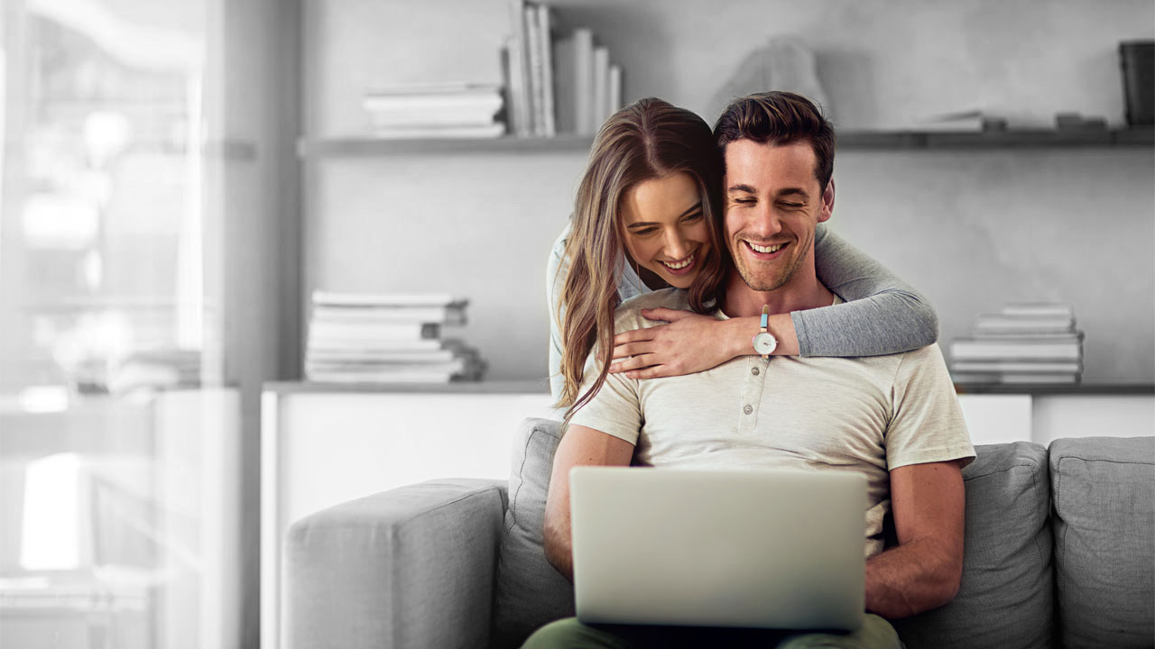 A pair of couple viewing the laptop together in sofa; image used for HSBC Australia Save together to maximise your money.