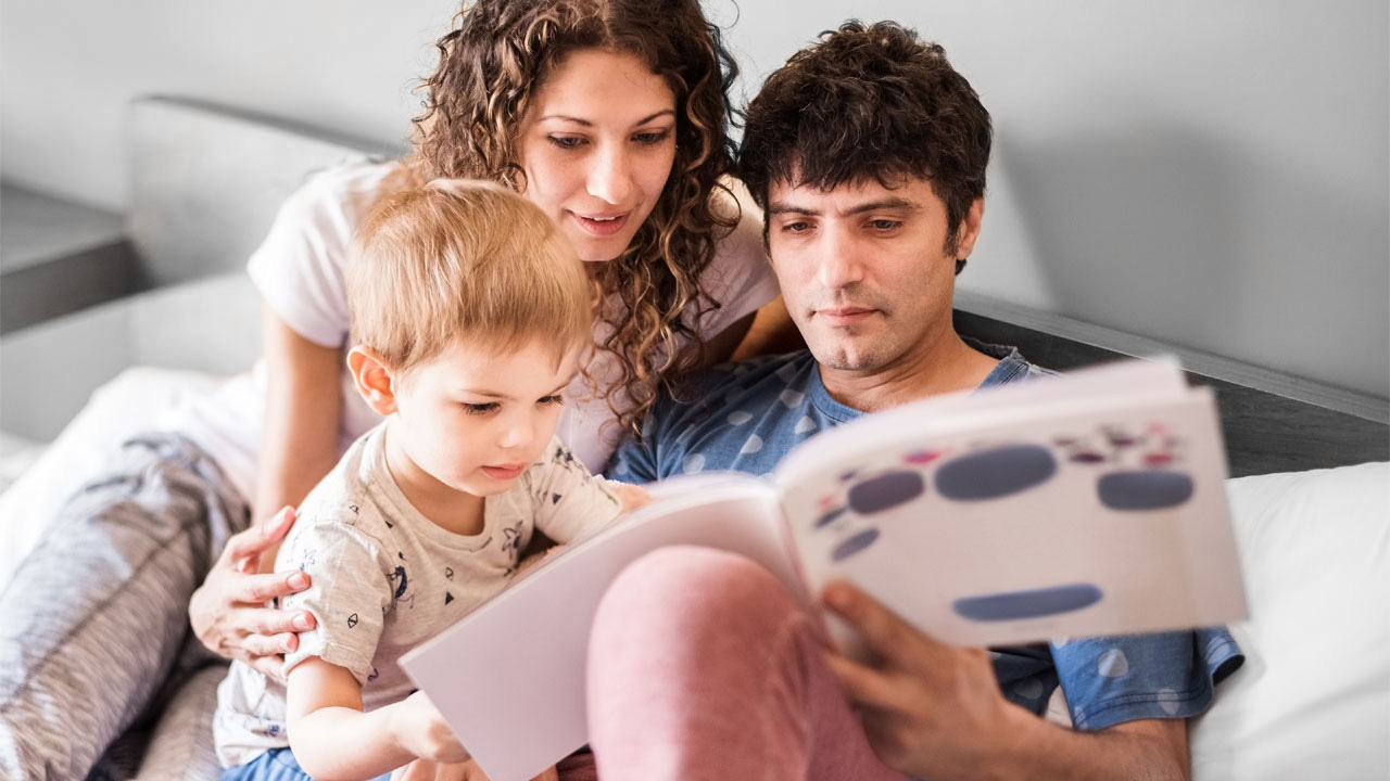 Parents reading book with their child; image used for HSBC Australia Why you should start saving for your child's education today.
