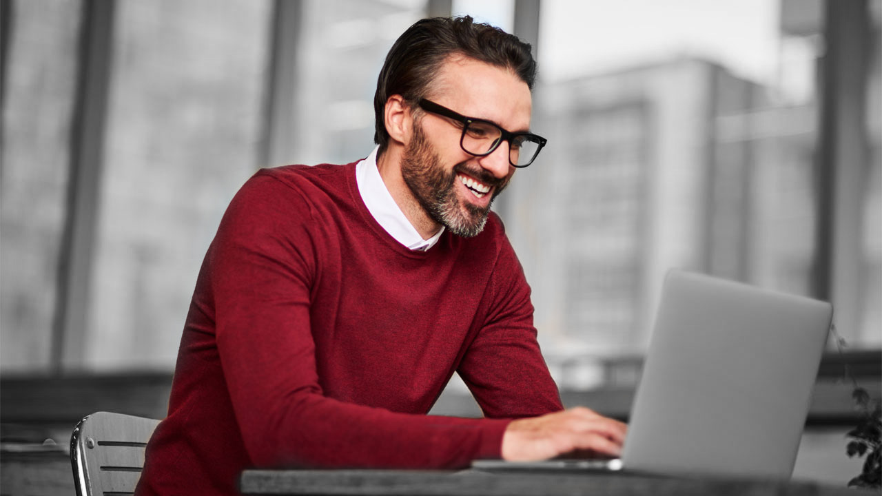 A smiling businessman using laptop indoor; image used for HSBC Australia 4 practical tips for your retirement plan.