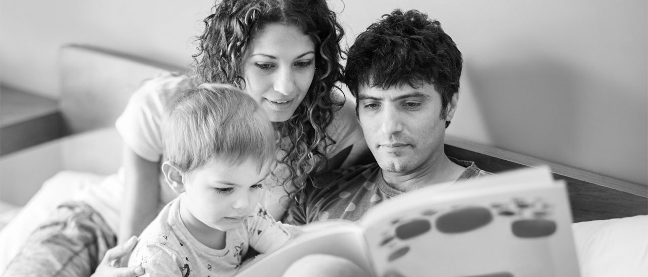 Parents reading book with their child; image used for HSBC Australia Why you should start saving for your child's education today.